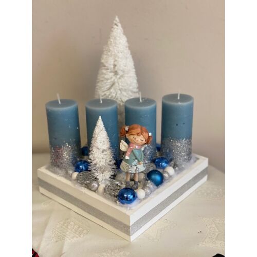 Fehér fa láda díszítve kék-ezüst csillámos gyertyákkal, fehér havas fenyőfákkal, kék üveg gömbökkel, ezüst és fehér termésekkel, bogyókkal, kerámia kislánnyal, hideg fényű led világítással-karácsonyi dekoráció-álom ker